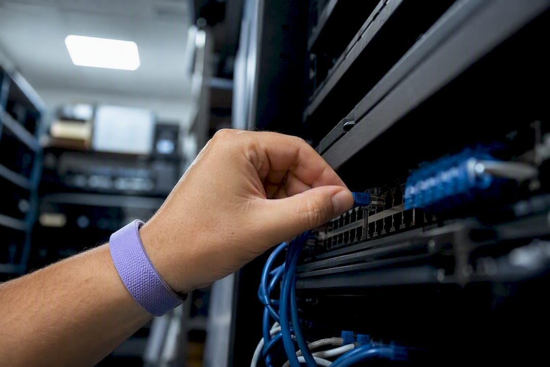 Hand plugging network cable in server room