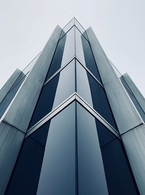 Upward view of a glass office tower against a pale sky
